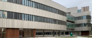 Contemporary office building with vertical metal panels and large glass windows along a curved façade.
